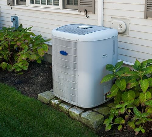Outdoor AC unit next to a house, part of a residential AC and furnace replacement system.